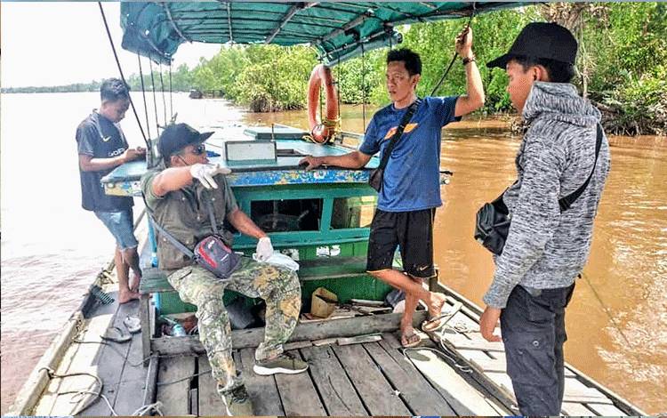 Komandan BKSDA Sampit Pos Jaga Sampit, Muriansyah bersama warga saat mencari bangkai buaya yang hanyut di Sungai Mentaya.