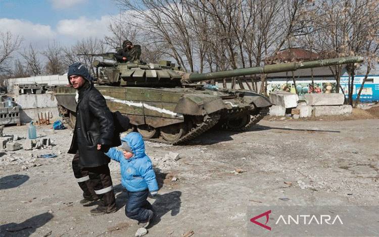 Arsip - Seorang warga berjalan dengan seorang anak melewati tank pasukan pro Rusia selama konflik Ukraina-Rusia di kota pelabuhan Mariupol yang terkepung, Ukraina, 18 Maret 2022. (ANTARA/Reuters/Alexander Ermochenko/as)