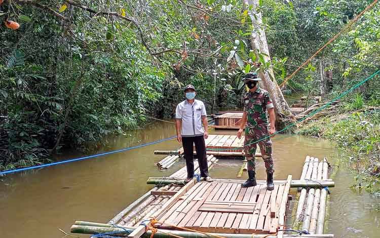 Kepala Desa Tewah Pupuh, Ardianto bersama Babinsa TNI Pratu Ahmad Asmawi saat meninjau keramba ikan yang ditempatkan di Sungai Tewah.