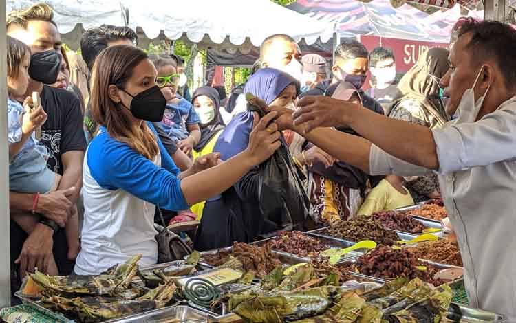 Seorang pedagang lauk pauk di Pasar Ramadan saat melayani pembeli. 