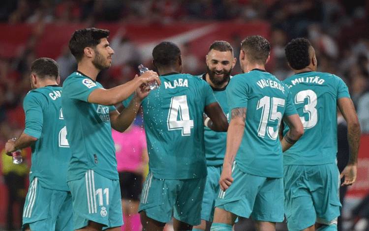 Striker Real Madrid Karim Benzema merayakan gol bersama rekan-rekan satu tim dalam pertandingan LaLiga Spanyol antara Sevilla FC dan Real Madrid CF di Stadion Ramon Sanchez Pizjuan di Seville pada 17 April 2022. (AFP/CRISTINA QUICLER)