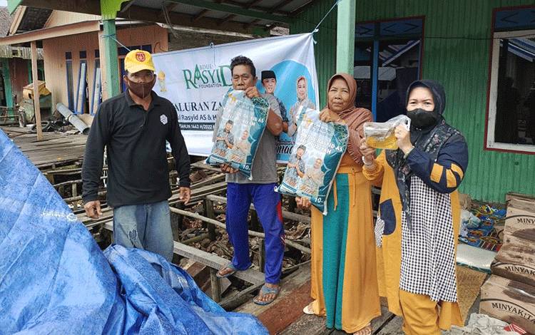Ritawati dari CBI Group, sebagai perwakilan keluarga H Abdul Rasyid AS dan Hj Nuriyah saat menyerahkan paket beras dan minyak goreng kepada penerima di Kuala Pembuang.