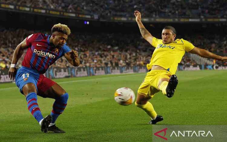 Pemain Barcelona Adama Traore berebut bola dengan pemain Cadiz Luis Alfonso Espino pada lanjutan Liga Spanyol di Camp Nou, Barcelona, Spanyol, Senin (18/4/2022). Barcelona tumbang di kandang melawan tim papan bawah Cadiz dengan skor 0-1