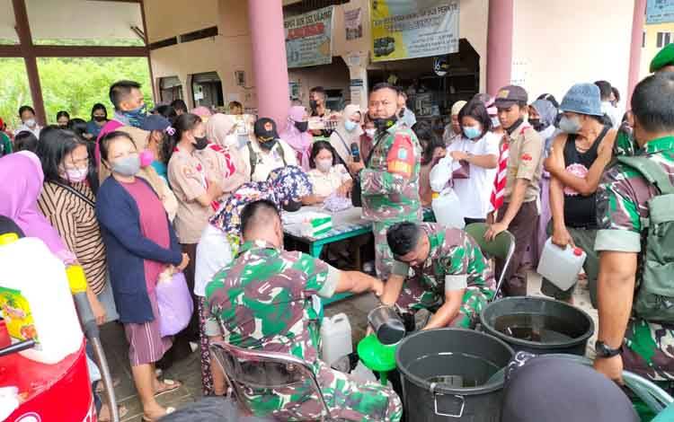 Anggota TNI sedang mengisi minyak goreng murah ke dalam teng 5 liter milik warga