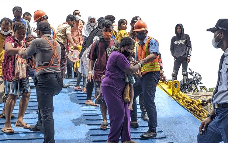 Sejumlah penumpang KM Kirana III saat dibantu para petugas ketika masuk ke dalam kapal.
