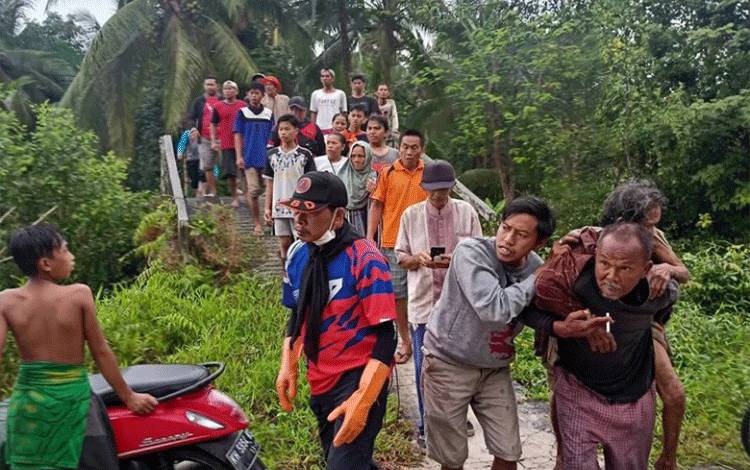 Seorang warga saat membopong seorang nenek yang ditemukan lemas di kebun kelapa setelah 4 hari hilang.