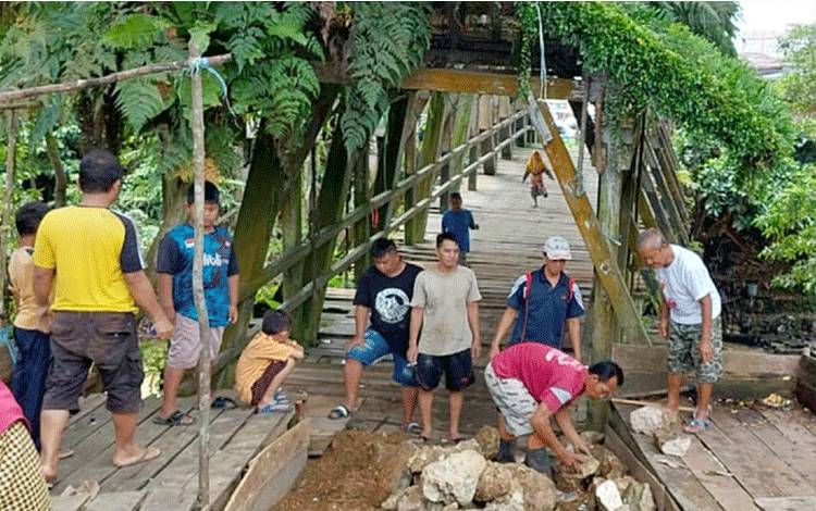 Warga Kelurahan Ampah Kota bergotong royong memperbaiki jembatan ulin peninggalan zaman Belanda yang juga disebut Jembatan Belanda.