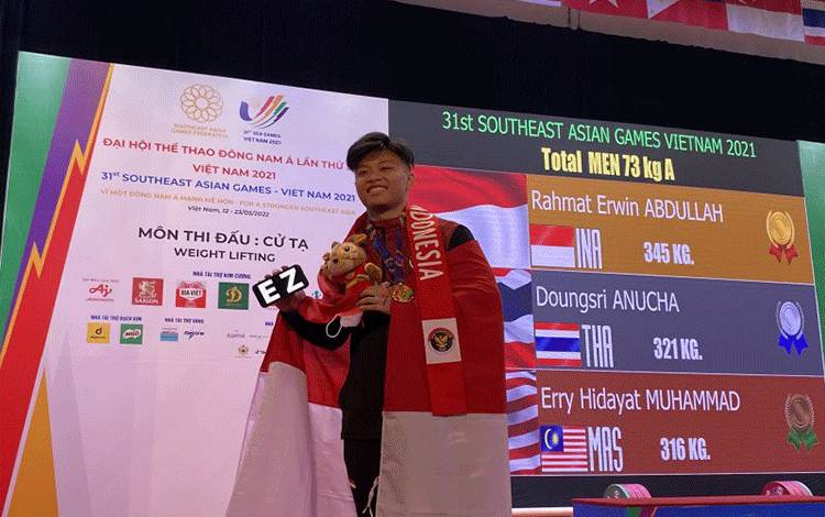 Lifter Indonesia Rahmat Erwin Abdullah berpose memperlihatkan medali emas angkat besi kelas 73kg SEA Games di Hanoi Sports Training Center, Hanoi, Vietnam, Sabtu (21/5/2022). (ANTARA/Shofi Ayudiana)