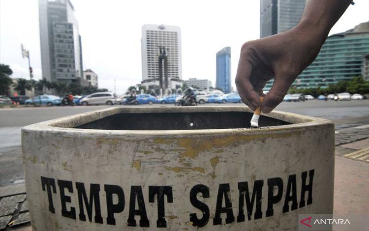 Warga membuang puntung rokok ke dalam tempat sampah di Kawasan Bundaran HI, Jakarta, Minggu (17/11).(ANTARA FOTO/ZABUR KARURU)