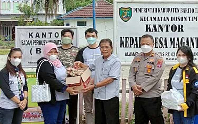 Kepala SMAN 1 Tamiang Layang, Istiqomah menyerahkan secara simbolis bantuan bahan makanan dan obat-obatan bagi warga korban banjir kepada Pemerintah Desa Magantis