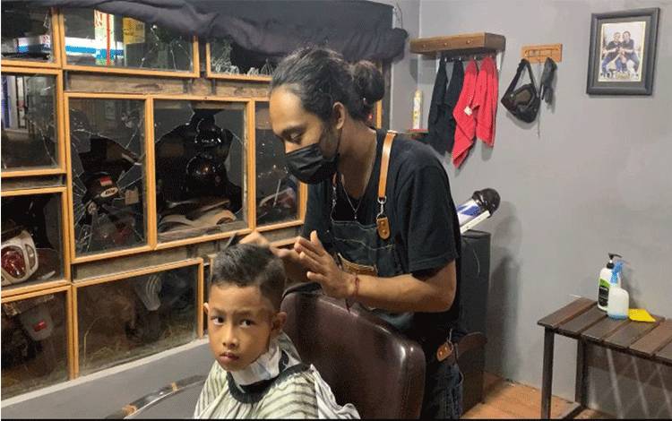 Seorang anak saat memangkas rambut di tempat Babershop Cafe Jingga yang dirusak oleh anggota gengmotor.