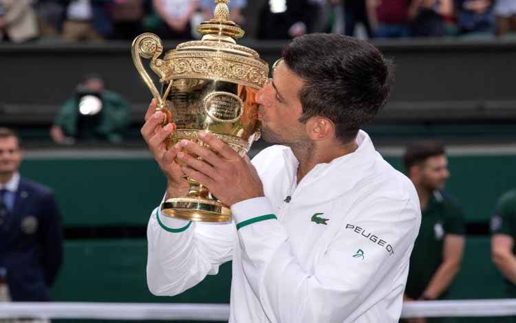 Petenis Serbia Novak Djokovic mencium piala kemenangannya setelah bertanding melawan petenis Italia Matteo Berrettini dalam laga babak final tunggal putera Tenis  Wimbledon, di All England Lawn Tennis and Croquet Club, London, Inggris, Minggu (11/7/2021)