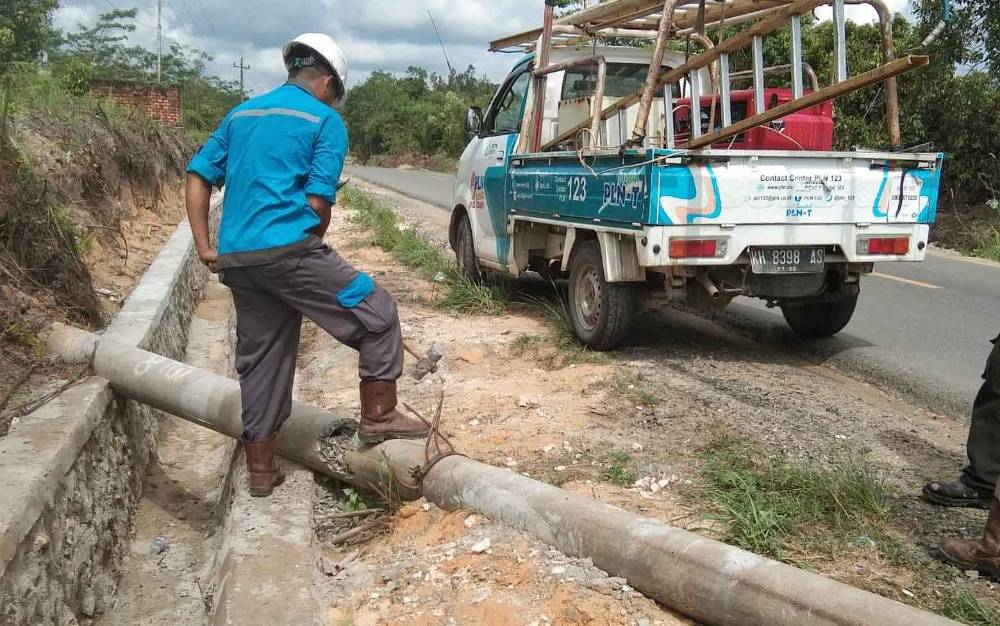 Petugas PT PLN ULP Buntok berupaya menyingkirkan tiang listrik bekas yang melintang di atas parit dan bahu jalan di Desa Simpang Kabupaten Barito Timur