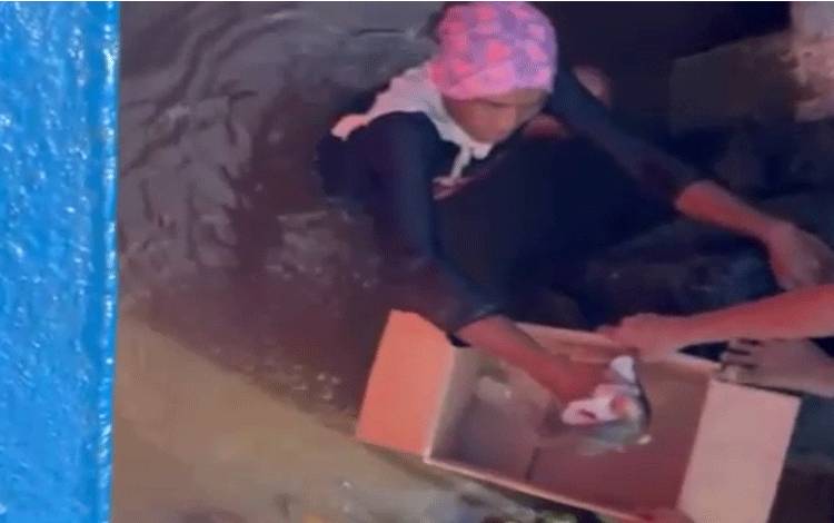Seorang warga saat melakukan evakuasi terhadap jenazah bayi yang ditemukan mengapung di Sungai Mentaya.