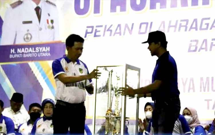 Bupati Barito Utara, H Nadalsyah menerima piala bergilir yang diserahkan Camat Teweh Tengah untuk diperebutkan kembali pada pelaksanaan Porkab Barito Utara di Stadion Swakarya Muara Teweh, Selasa 21 Juni 2022 malam.