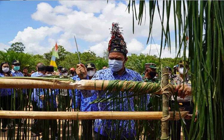 Bupati Lamandau Hendra Lesmana memotong pantan pamali sebagai bentuk penyambutan di Kampung Kerukunan Sejahtera di Desa Bukit Indah Kecamatan Bulik.