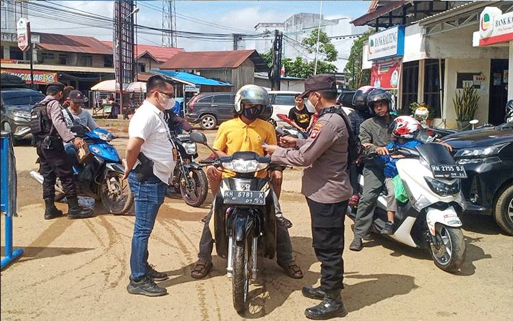 Petugas memeriksa kartu vaksin pengendara sepeda motor saat razia vaksin di Bundaran Kota Ampah Kecamatan Dusun Tengah.