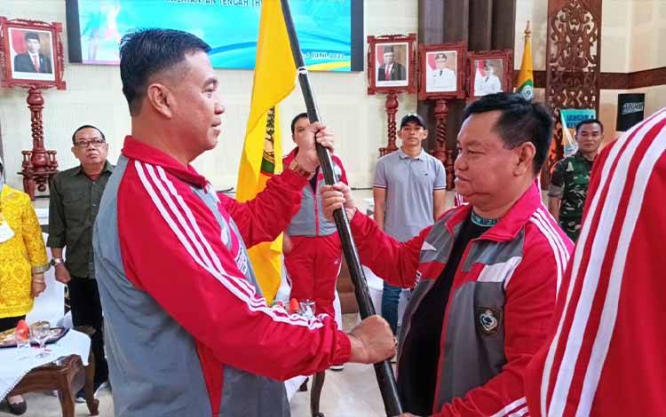 Bupati Kotim, Halikinnor menyerahkan bendera kepada Kadispora Kotim Wim RK Benung pada saat memberangkatkan atlet Popprov Kotim.