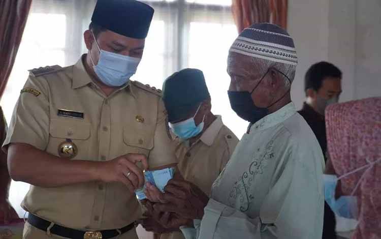Bupati Lamandau Hendra Lesmana menyerahkan bansos tunai kepada salah satu warga di Kecamatan Sematu Jaya.