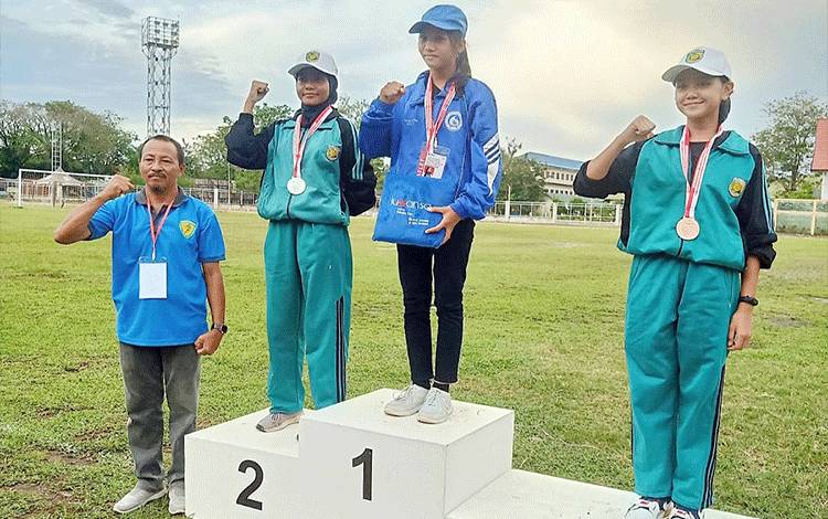 Ketua Umum Pengkab PASI Barito Timur Surya Ahmadi (paling kiri) mendampingi atlet putri peraih medali emas.