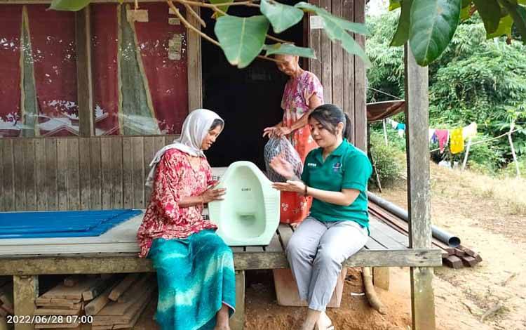 Kasi Pemberdayaan dan Pembinaan Masyarakat Desa Kalamus, Elpina Hartati saat menyerahkan bantuan material MCK kepada rumah tangga miskin