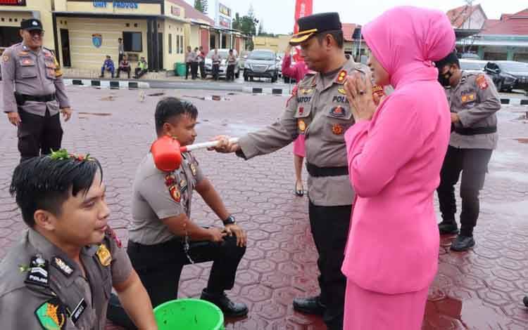 Kapolres Seruyan AKBP Gatot Istanto saat melakukan siraman kepada salah satu personel pada upacara korp raport kenaikan pangkat