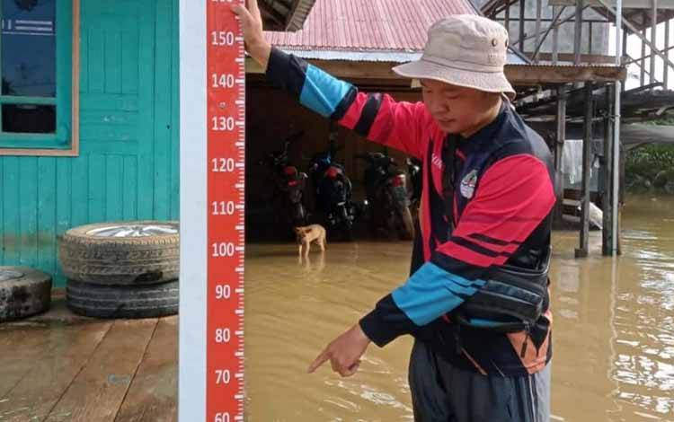 Petugas memantau ketinggian air melalui patok pencegahan dini oleh BPBD Kotim di Desa Tumbang Mujam, Kecamatan Tualan Hulu.