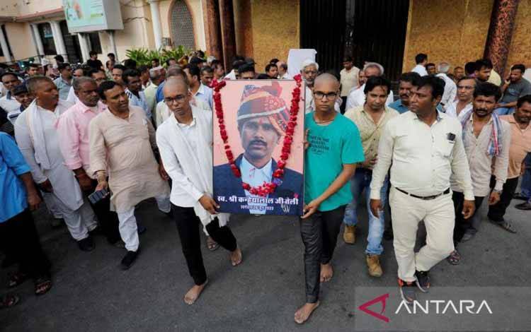 Dua putra Kanhaiyalal Teli, seorang penjahit Hindu, yang diduga dibunuh oleh dua pria dari komunitas Muslim minoritas, membawa potret ayah mereka setelah pertemuan doa di Udaipur, negara bagian Rajasthan, India, 30 Juni 2022