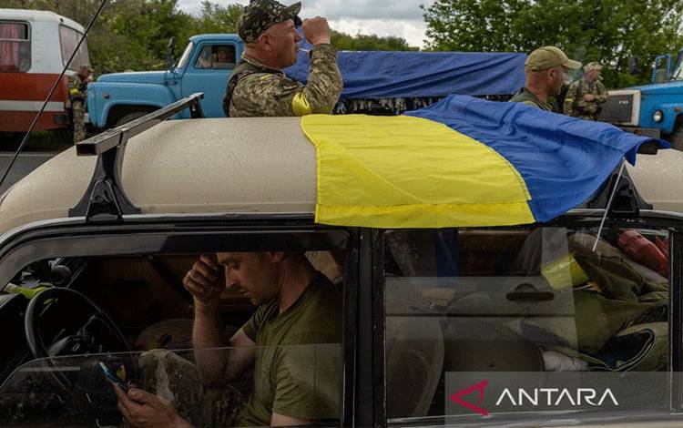 Seorang tentara Ukraina duduk di mobil Lada-nya memeriksa teleponnya saat tentara dan sukarelawan dari pasukan pertahanan teritorial berhenti di jalan ketika konvoi dalam perjalanan ke front timur, dekat Oleksandriya, Ukraina, Minggu (15/5/2022). ANTARA FOTO/REUTERS/Jorge Silva/pras/sad.
