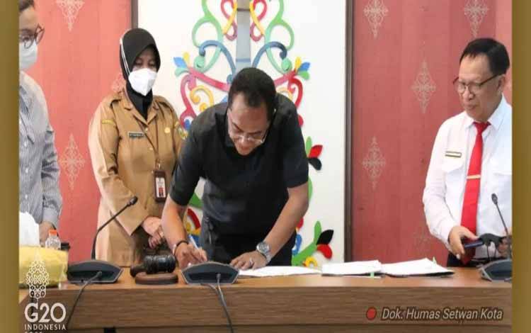 Ketua DPRD Palangka Raya, Sigit K Yunianto menandatangani perjanjian kerja sama 3 Raperda inisiatif bersama UPR di ruang Komisi DPRD, Selasa 4 Juli 2022. (Foto: Humas Setwan Kota)