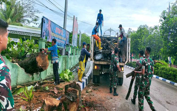 Anggota Kodim 1013 Muara Teweh saat membersihkan batang pohon yang tumbang ke bahu jalan di Jalan A Yani Muara Teweh, Kamis 14 Juli 2022. (foto: Dhani)