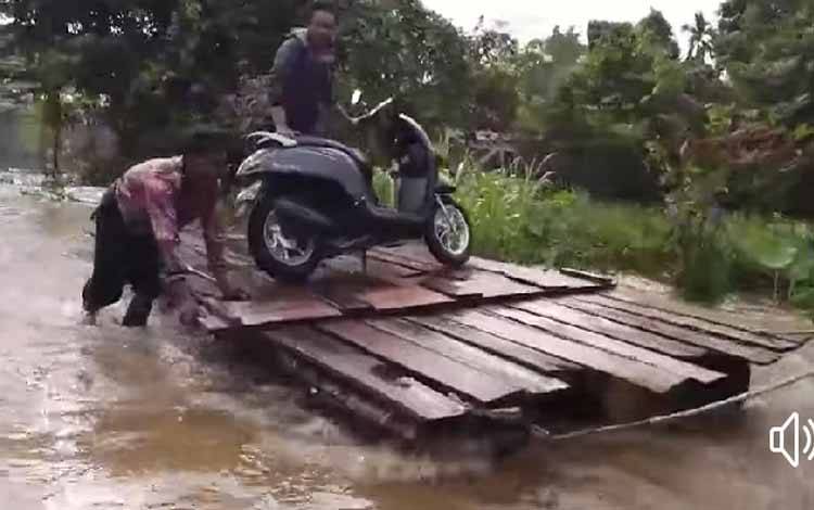 Seorang warga bersama kendaraannya harus menggunakan jasa penyeberangan milik warga untuk melewati jalan yang banjir di Kecamatan Katingan Tengah, Minggu 7 Agustus 2022