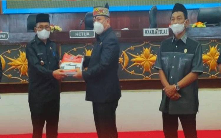 Wabup Mura Rejikinoor saat menyerahkan dokumen KUA/PPAS RAPBD 2022 yang diterima langsung Ketua DPRD Mura, Doni. (foto trisno)