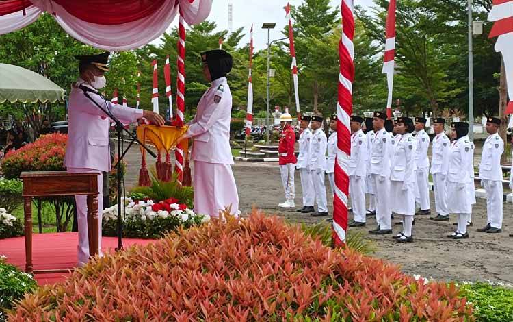 Bupati Seruyan, Yulhaidir menyerahkan bendera merah putih untuk dikibarkan pada Upacara Peringatan HUT Ke-77 Kemerdekaan Republik Indonesia, Rabu, 17 Agustus 2022 (Foto : Fahrul)