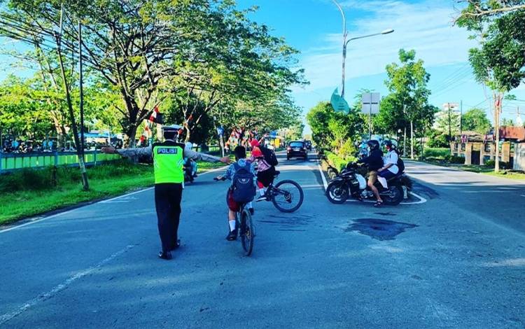 Personel Satlantas Polres Kapuas saat bantu anak sekolah menyeberang jalan pada Kamis, 18 Agustus 2022. (FOTO: DODI)