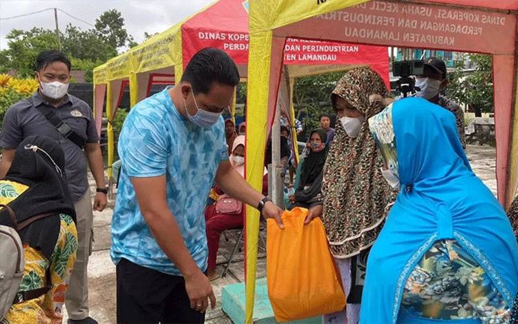 Bupati Lamandau Hendra Lesmana menyerahkan paket sembako di gelaran pasar murah yang diselenggarakan di Halaman Kantor Kecamatan Bulik. (FOTO : HENDI NURDALAH)