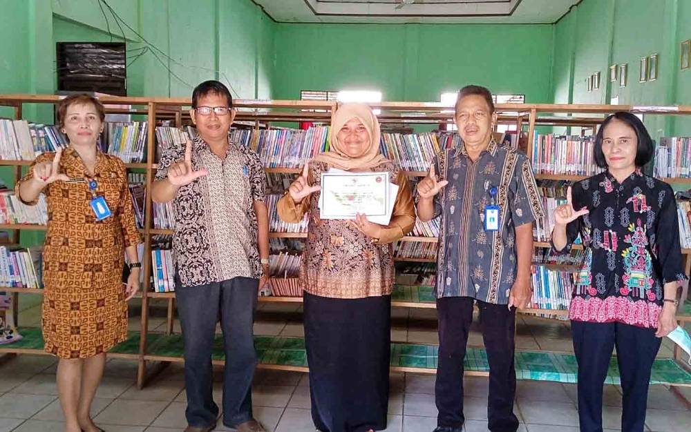 Kepala SMAN 1 Tamiang Layang Istiqomah (tengah) memegang sertifikat akreditasi C dari Perpustakaan Nasional RI, Kamis, 22 September 2022. (FOTO: BOLE MALO)