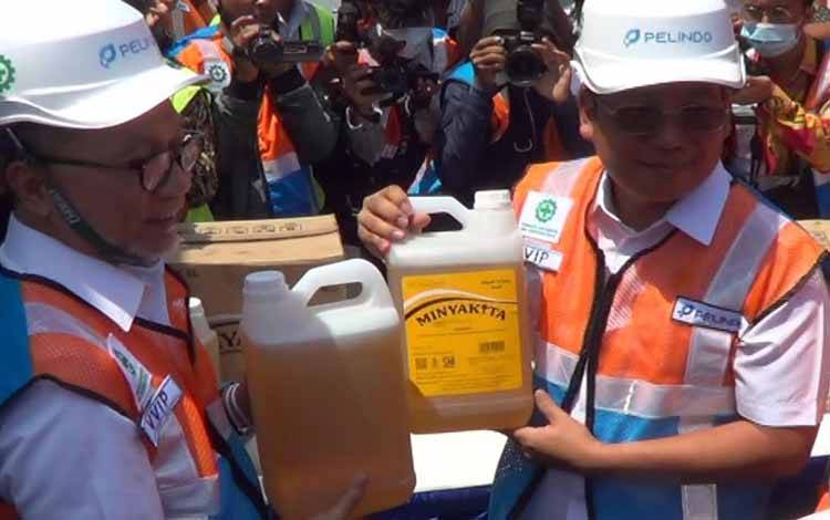 Mendag Zulkifli Hasan (kiri) menunjukkan minyak goreng kemasan ukuran lima liter sebagai salahbsatu yang akan dikirim ke Maluku Utara menggunakan kapal tol laut melalui Pelabuhan Tanjung Perak Surabaya, Sabtu. (ANTARA/Hanif Nashrullah)