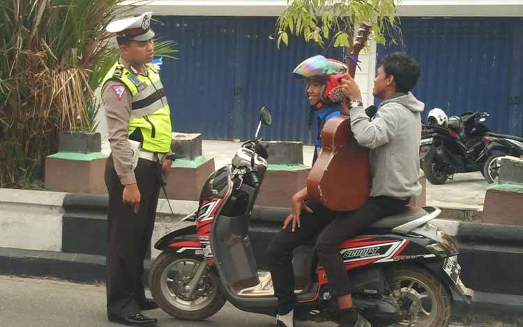 Seorang anggota Satlantas Polres Kotim saat menghentikan pengendara yang tidak menggunakan helm di jalan raya Sampit. (FOTO: HAMIM)
