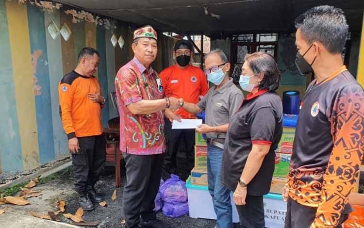 Kepala Pelaksana BPBD Kapuas Panahatan Sinaga saat menyerahkan bantuan warga terdampak kebakaran rumah di Jalan Sulawesi, Jumat, 30 September 2022. (FOTO: BPBD KAPUAS)