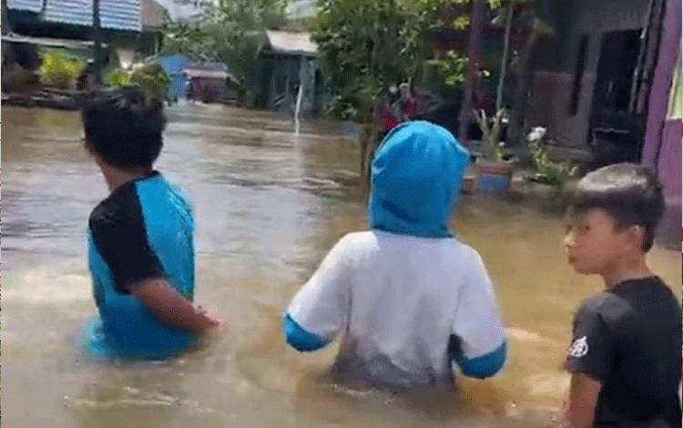 Sejumlah warga saat melintas ditengah kondisi banjir yang melanda desa mereka, beberapa waktu lalu.