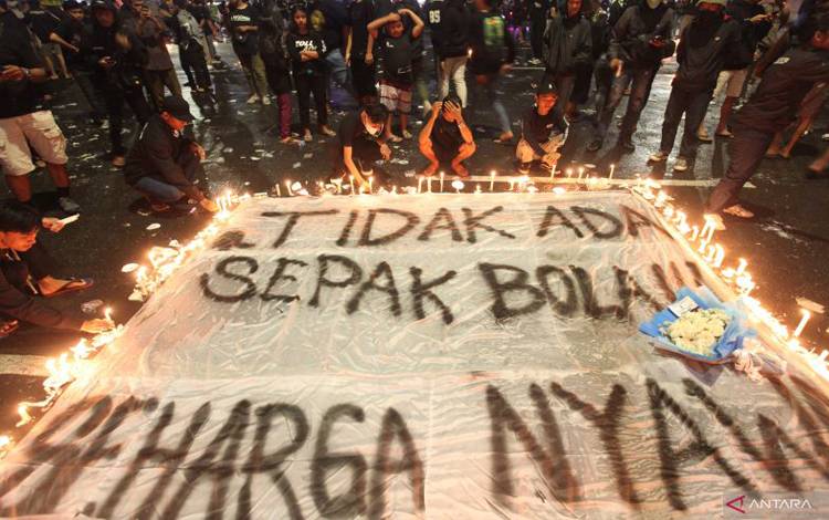 uporter Persebaya menyalakan lilin saat mengikuti doa bersama di Tugu Pahlawan, Surabaya, Jawa Timur, Senin (3/10/2022). ANTARA FOTO/Didik Suhartono/hp.