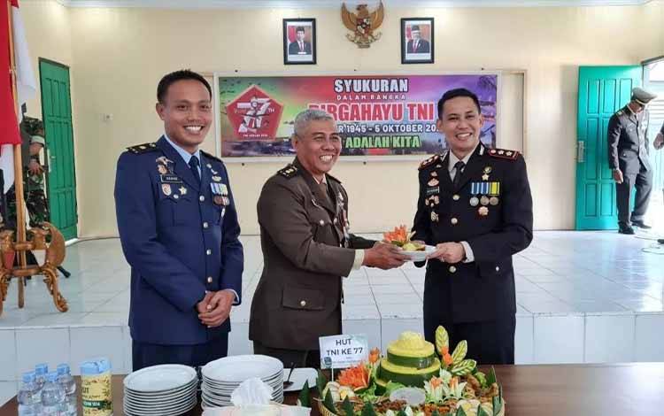 Kasdim Letkol Inf Edy Sucipto menyerahkan potongan tumpeng pada Kapolres Kobar AKBP Bayu Wicaksono dalam acara syukuran HUT TNI yang ke-77. (FOTO: DANANG)