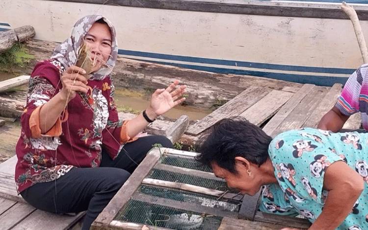 Anggota DPRD Kapuas Sri Umi Daryatun saat menunjukkan udang dan ikan hasil tangkapan warga di Desa Tumbang Mangkutup. (FOTO: IST)