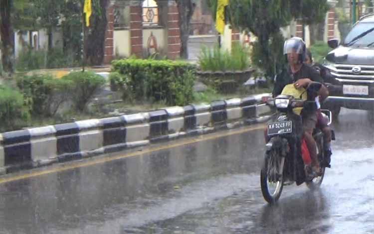Pengendara motor dan mobil saat melintas di Jalan A Yani, yang saat bersamaan sedang dilanda hujan