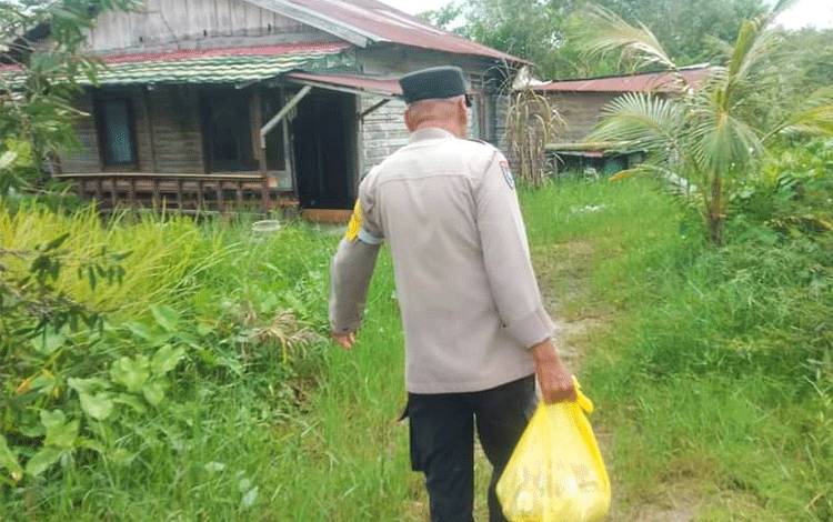 Bhabinkamtibmas Kelurahan Menteng, Aipda Toha menyambangi dan memberikan bantuan sosial berupa paket sembako kepada warganya yang mengalami sakit lumpuh, Jumat, 21 Oktober 2022. (POTO : PARLIN TAMBUNAN)