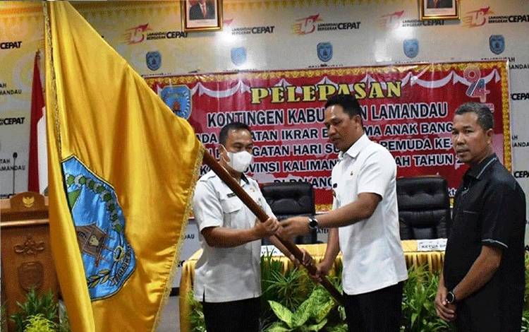 Bupati Lamandau Hendra Lesmana menyerahkan Pataka Kabupaten Lamandau kepada ketua Kontingen IBAB Kabupaten Lamandau. (FOTO : HENDI NURFALAH)
