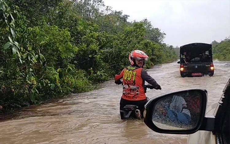 Ketua HNR Adventure Trail Ramadansyah yang terhenti ditengah banjir, untuk mengatur jalan mobil pembawa paket sembako melintas.