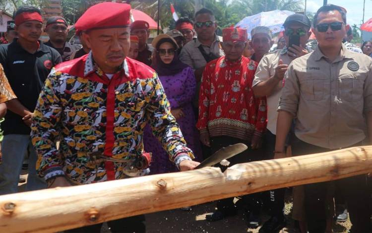 Bupati Seruyan, Yulhaidir melakukan prosesi adat potong pantan, saat menghadiri Syukuran Hari Jadi ke-203 Desa Bangkal ( FOTO: PROKOM SERUYAN)