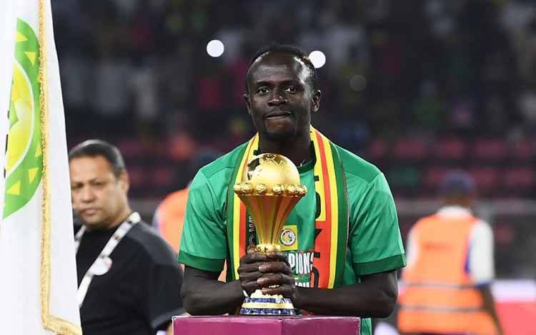 Sadio Mane bersama trofi juara Piala Afrika 2021 setelah memenangkan laga final melawan Mesir di Stade d'Olembe di Yaounde, Kamerun, pada 6 Februari 2022. (AFP/CHARLY TRIBALLEAU)